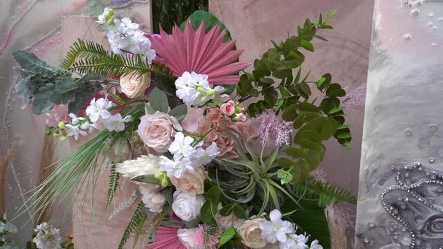 Close shot of beautiful flower composition. Wonderful roses of different color and a lot of greenery. Floral design, decoration for important events. White, purple and pink roses. Expensive febric