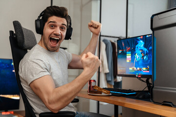 Excited guy making winner gesture while playing video game on computer