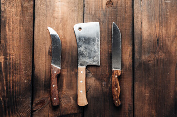 set of different kitchen knives with wooden handles on a brown background from boards
