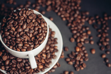 a cup with coffee beans stands on a saucer on a gray background close-up