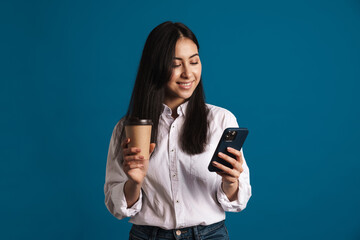 Happy beautiful asian girl drinking coffee while using smartphone