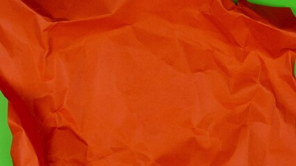 Stop motion animation. Red paper unfolds from a paper ball and then wrinkles and disappears on green background