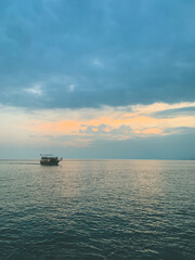 Lonely boat on the sea horizon, beautiful  cloudscape, orange twilight