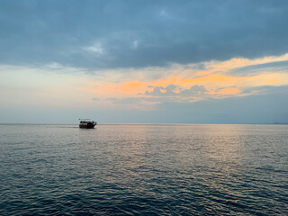 Lonely boat on the sea horizon, beautiful  cloudscape, orange twilight
