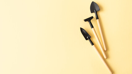Miniature home gardening tools on beige background.