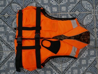 A neoprene black protective mask on an orange life jacket on the floor of the pool. Compliance with...