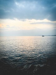 Lonely boat on the sea horizon, beautiful  cloudscape, orange twilight