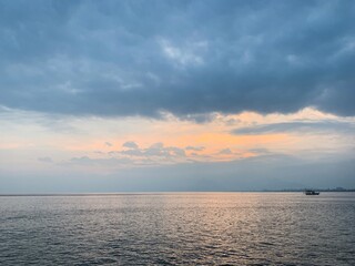 Lonely boat on the sea horizon, beautiful  cloudscape, orange twilight