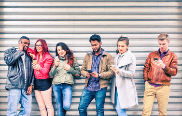 Group of multiracial friends using mobile phone standing in line outdoors -  Multicultural...