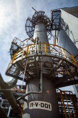 Distillation column on blue sky. Tilt-shifted partially blurred and wide-angle view.