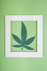 Mock up white frame and cannabis marihuana leaf over light green background.