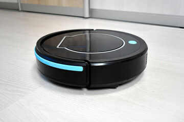 Robot vacuum cleaning on laminate wood floor. Modern digital technology. Innovation artificial intelligence housekeeping. Lifestyle concept. Smart house.