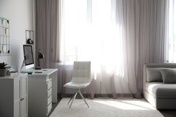 Comfortable white chair near desk in stylish office interior