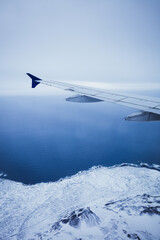 Top view from inside window airplane of a cold atmosphere and wing over Iceland landscape