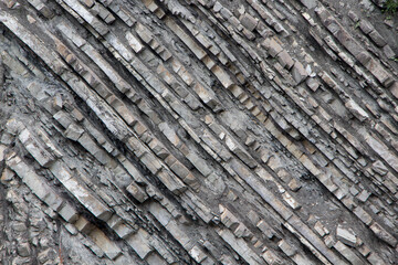 Fototapeta premium The surface of an old rock with cracks and moss. Old rock texture (wild background) 