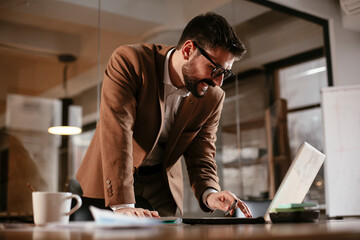 Young businessman working on laptop in his office. Handsome man having video call.