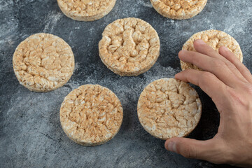 Male hand holding rice cake on marble background