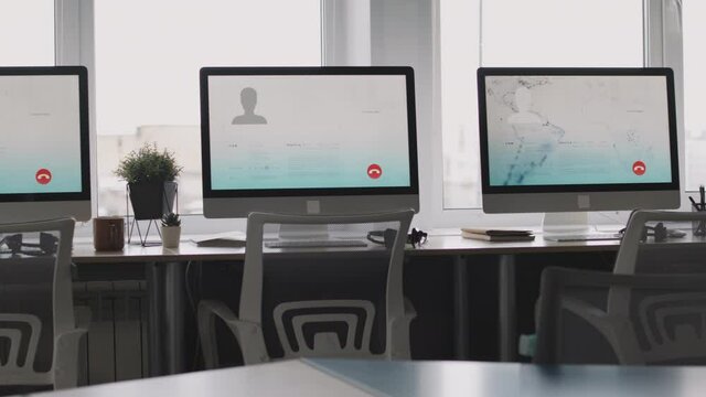 PAN shot of interior of empty call center office. Computer monitors with interface of customer service software standing on desks by panoramic windows