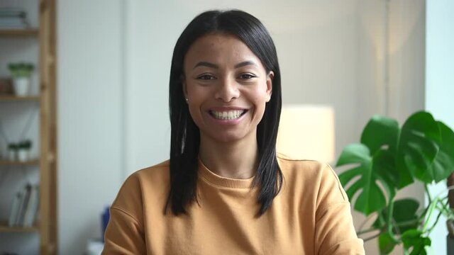 African woman on background of house happy and beautiful Spbd. Female model with black skin on face smiling near white teeth at home. Cheerful person looks directly at closeup near houseplant in room