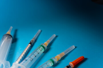 Various types of syringes with caps to protect their needles, seen from a slightly elevated...
