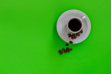 white cup with coffee on the green panel. view from the top