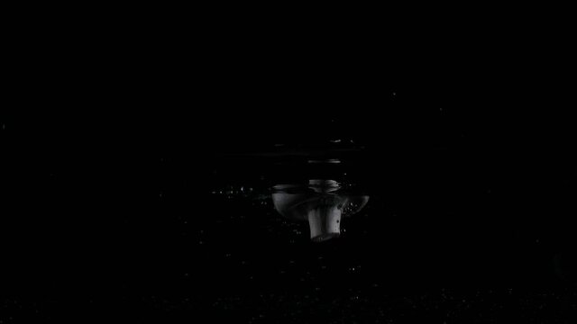 Three white mashrooms\champignons dropped falling in water with lot of splashes, bubbles and drops on black background closeup