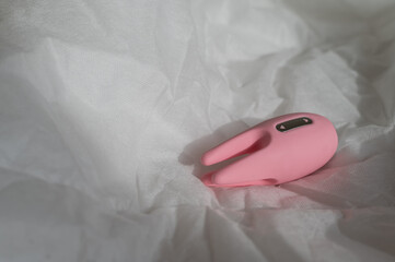 Close-up of a clitoral vibrator on a white sheet on the bed