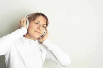 Portrait of smiling pretty woman enjoying music with white headphones on white background