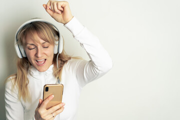 Portrait of smiling pretty woman enjoying music with white headphones on white background