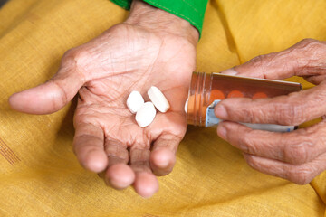 close up of pills and capsule on senior women's hand 