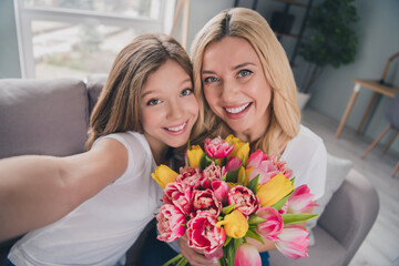 Photo of blonde girl and woman make selfie camera hold flowers tulips indoors inside house apartment