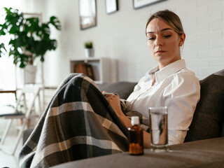 Young woman sick in bed holding glass of water..Woman drinking medicine.