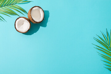 Obraz na płótnie Canvas Summer flat lay scene with palm leaf and coconut fruits on blue background. Top view, copy space. Trendy Summertime banner. Travel, organic cosmetics, summer sale concept.