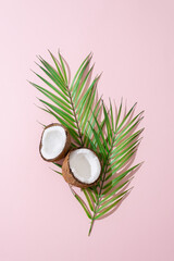 Obraz na płótnie Canvas Creative layout made of coconuts and leaves on pink background. Flat lay, top view. Food, summertime travel, natural cosmetics concept. Coconut on pink background.