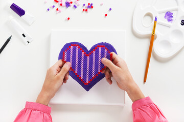 Ironing beads arts in the shape of heart and acrylic paint background on canvas. Kids crafts. Gift for Mather´s or Valentine's Day. Concept of family. Point of view shot.