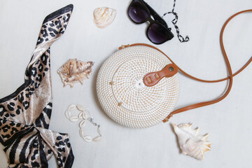 Summer fashion accessories on white. Rattan bag, black sunglasses and silk scarf.