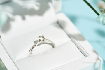 Top view on the gift box with engagement diamond ring on blue background