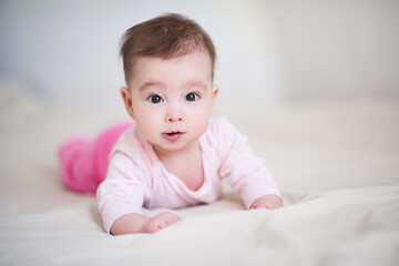 Cute baby under 1 year old wearing pajamas crawling in bed at home close up. Childhood. Good morning. Looking at camera. Healthy lifestyle.