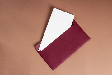 Postcard mockup horizontal, on a brown background, a red open envelope and a white sheet