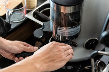 Bartender using coffee grinder. Male getting ready to make fresh espresso in coffee maker. Coffee machine makes coffee. Barista with Coffee Maker Machine grinder portafilter concept.