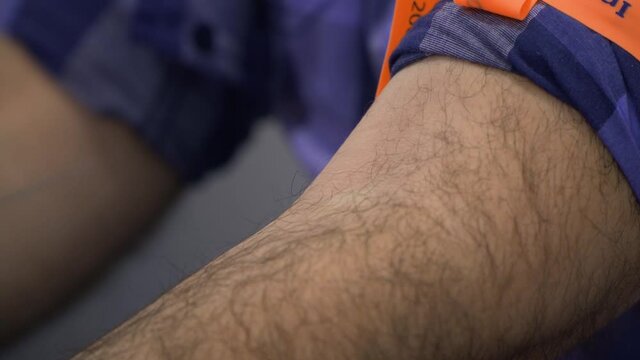 Side close-up, static shot of nurse with white gloves looking for veins before blood test. man is with a tourniquet on her arm.