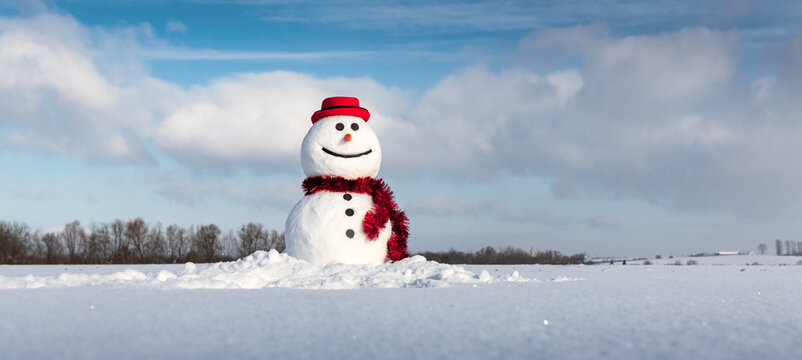 Funny snowman in stylish red hat and red scalf on snowy field. Panoramical photo ideal for site head mockup