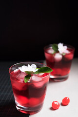 Copa de cóctel rojo con cerezas rojas sobre fondo negro y gris