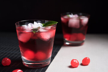 Copa de cóctel rojo con cerezas rojas sobre fondo negro y gris