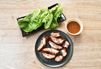 grilled pork bone slice dipping spicy chili sauce eat couple fresh cos lettuce vegetable on plate