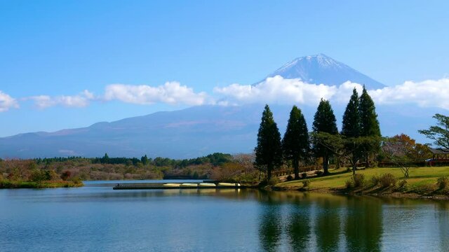 Timelapse of Fuji Mountain with lake and tree over blue sky and cloud at Tanuki Lake, Fujinomiya, Shizuoka Prefecture, Japan
