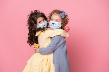 two girls in protective mask with colored eggs on pink background. Covid easter concept