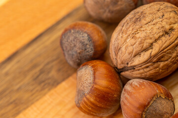 A mixture of hazelnuts and walnuts on a cutting board. Soft, artificial light, copy space available