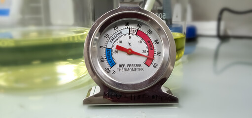 Refrigerator thermometer with colorful food in cold storage unit. Refrigeration safety gauge displaying safe food temperature.