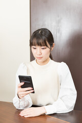 Naklejka premium Woman sitting on a chair and holding a smartphone